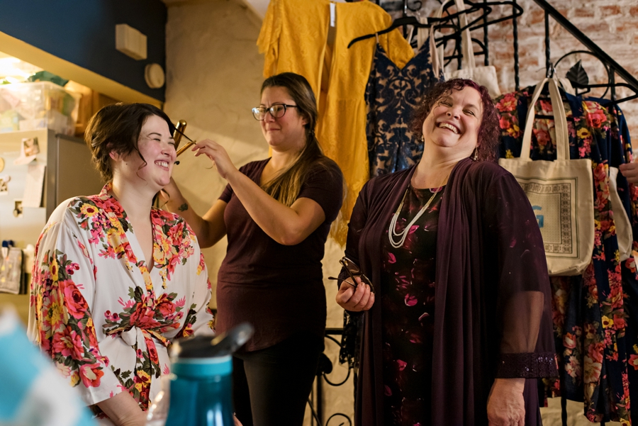 A mother laughs with her daughter while she gets her hair done before the wedding.